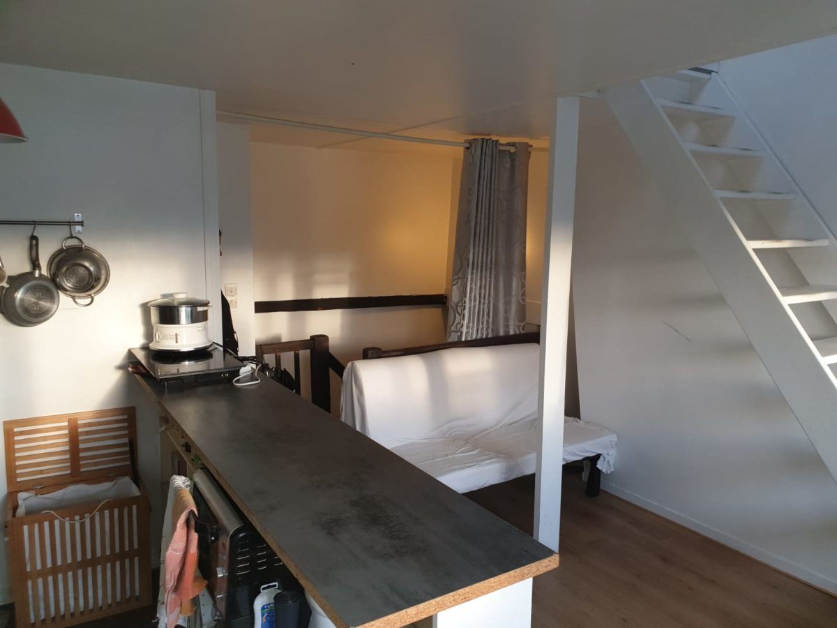 Le coin cuisine avec son bar, la banquette et l'escalier qui monte à la mezzanine.