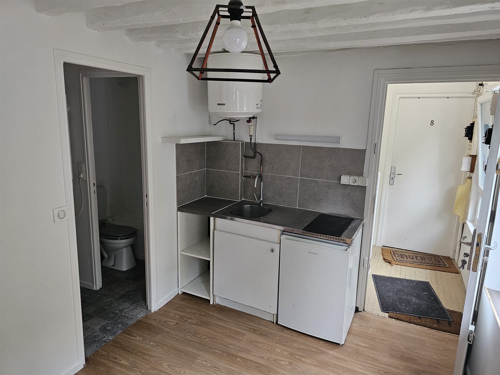 Le coin cuisine, la porte de la salle de bains et l'entrée sur le palier.
